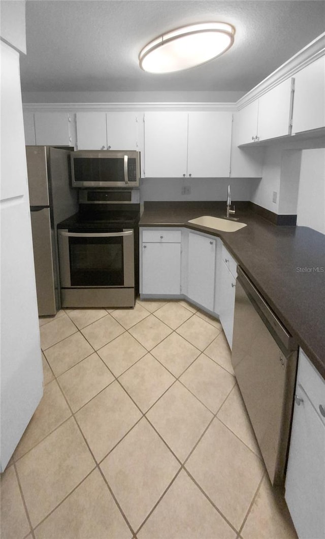 kitchen featuring white cabinets, sink, light tile floors, and stainless steel appliances