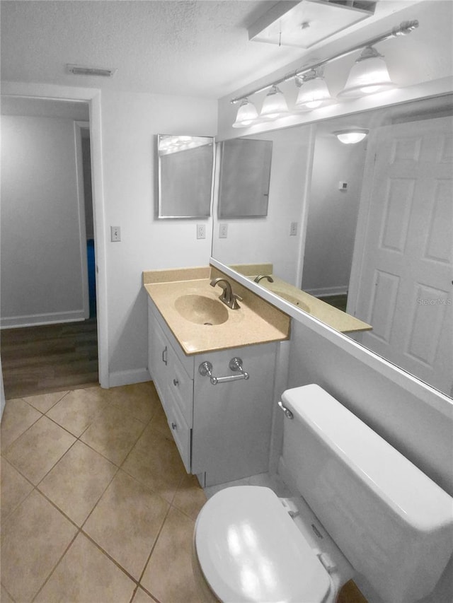 bathroom featuring tile flooring, vanity with extensive cabinet space, toilet, and a textured ceiling