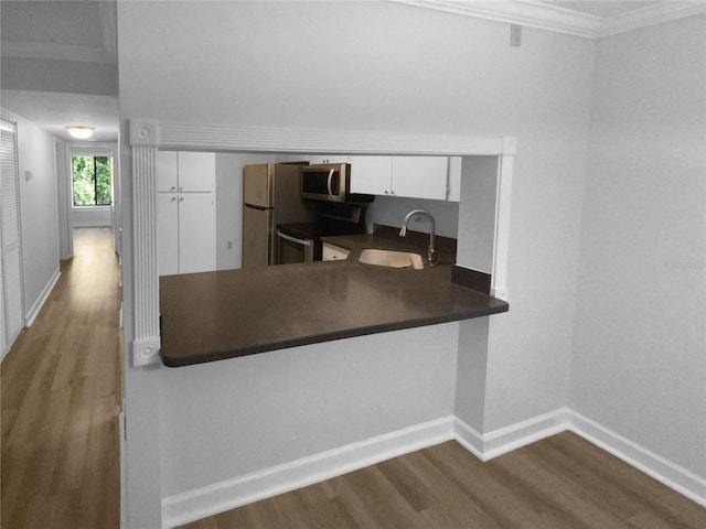 kitchen with sink, white cabinetry, hardwood / wood-style floors, stainless steel appliances, and ornamental molding