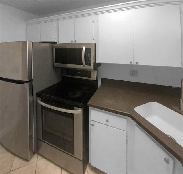 kitchen featuring sink, appliances with stainless steel finishes, white cabinets, and light tile floors