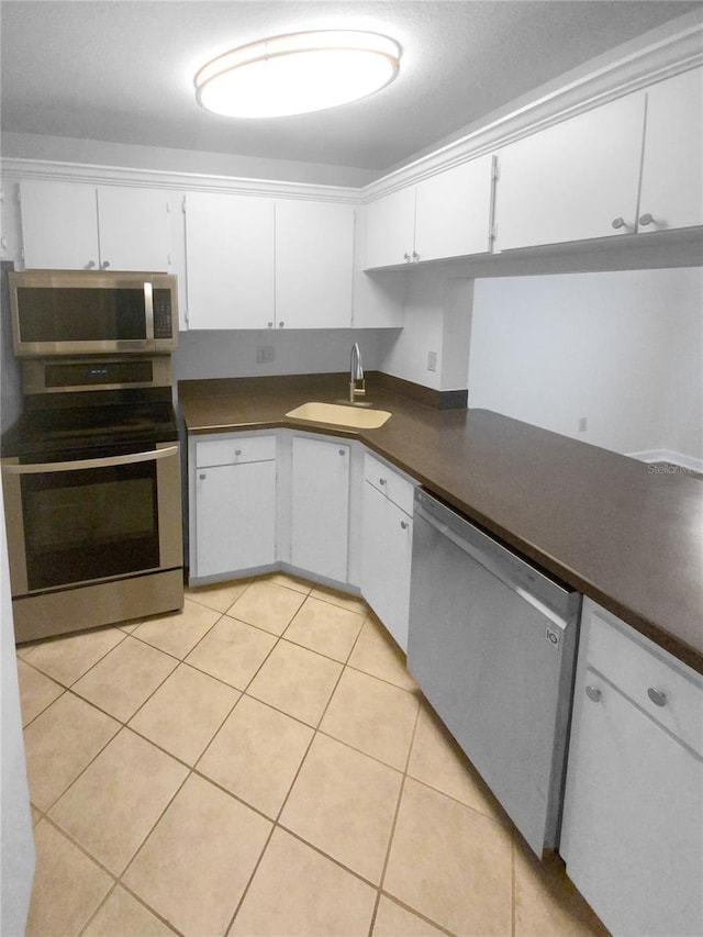 kitchen with sink, stainless steel appliances, light tile floors, and white cabinetry