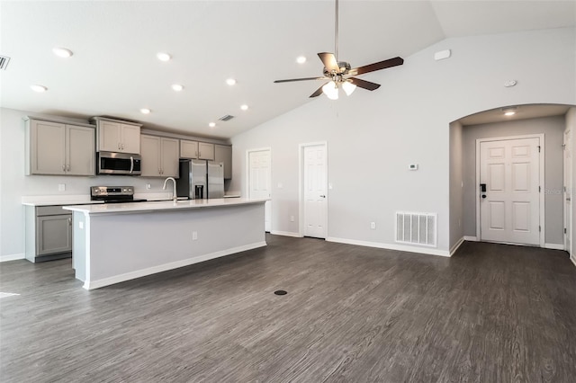 kitchen featuring dark hardwood / wood-style floors, high vaulted ceiling, stainless steel appliances, and an island with sink