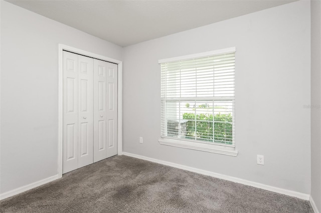 unfurnished bedroom with a closet and dark carpet