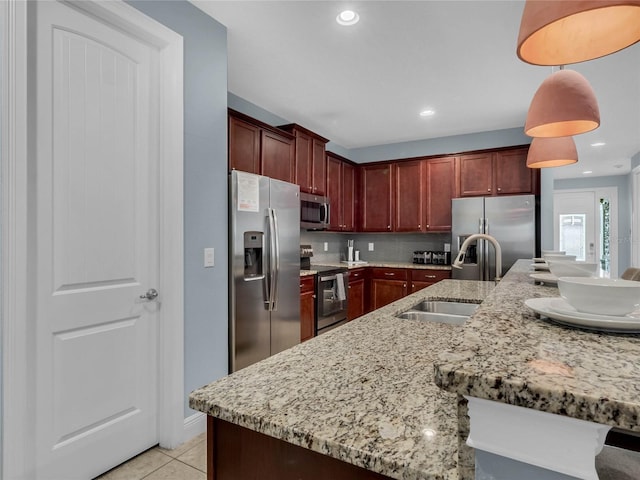 kitchen featuring light stone countertops, appliances with stainless steel finishes, tasteful backsplash, sink, and pendant lighting