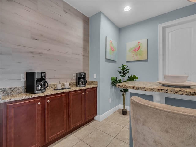 bar with wood walls, light stone countertops, and light tile floors