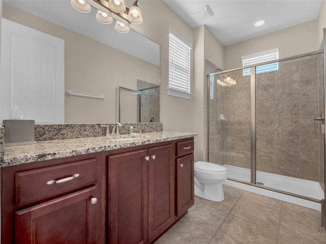 bathroom with a shower with shower door, toilet, tile flooring, and vanity