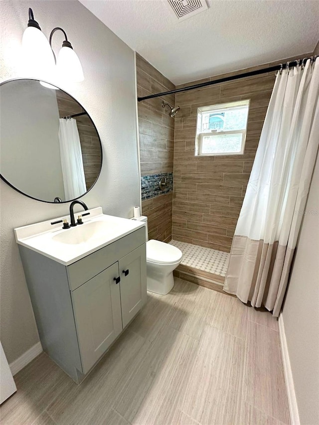 bathroom featuring curtained shower, tile floors, vanity, toilet, and a textured ceiling