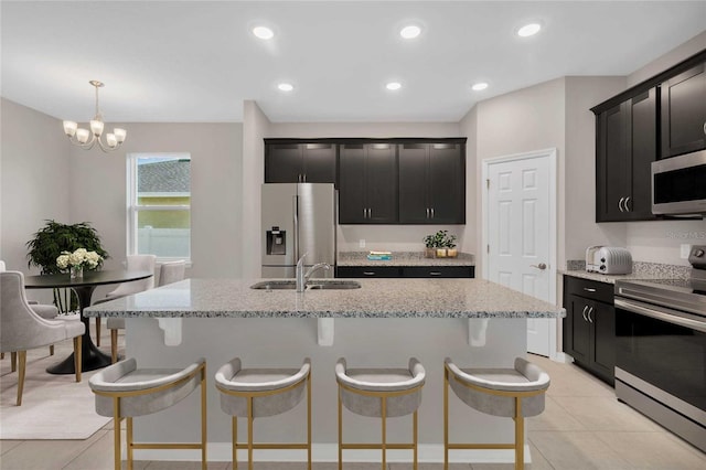 kitchen with sink, decorative light fixtures, stainless steel appliances, and an island with sink