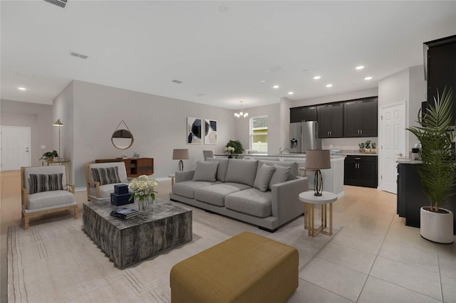 living room featuring an inviting chandelier, light tile patterned floors, and sink