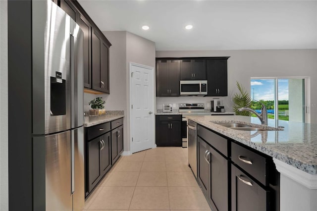 kitchen with appliances with stainless steel finishes, light stone countertops, sink, and light tile patterned floors