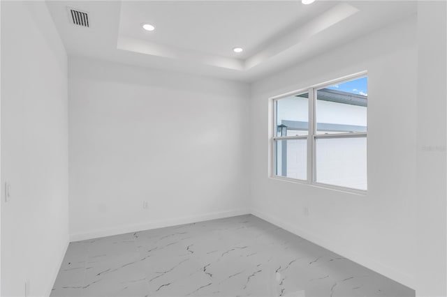 tiled spare room with a tray ceiling