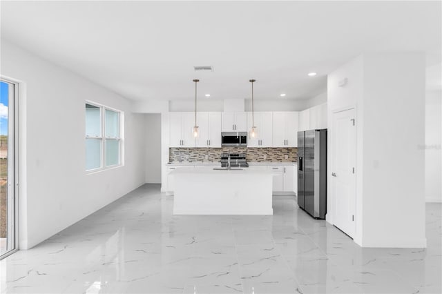 kitchen featuring hanging light fixtures, light tile flooring, appliances with stainless steel finishes, tasteful backsplash, and an island with sink