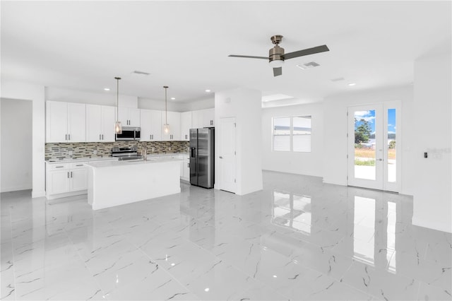 kitchen featuring decorative light fixtures, stainless steel appliances, an island with sink, white cabinetry, and light tile floors