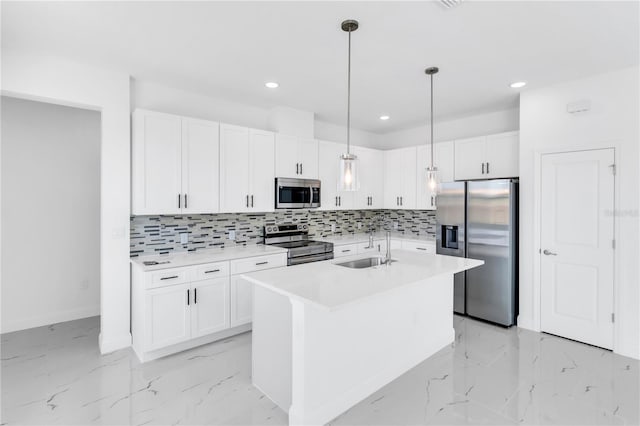 kitchen featuring decorative light fixtures, a center island with sink, white cabinetry, and stainless steel appliances