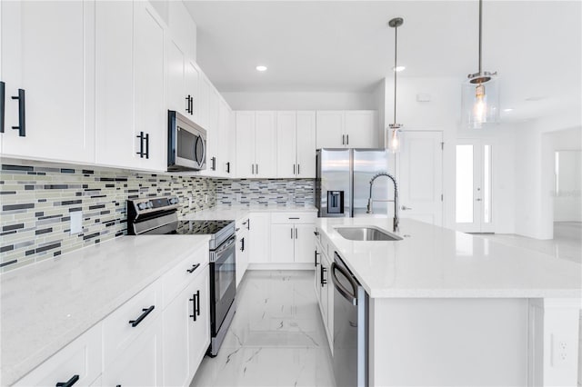 kitchen with appliances with stainless steel finishes, sink, light tile flooring, backsplash, and a kitchen island with sink