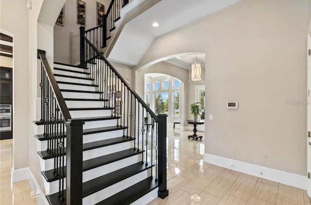 stairs with ornamental molding, a high ceiling, and light tile floors