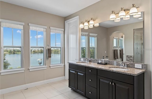 bathroom with a shower with door, a water view, large vanity, tile flooring, and dual sinks