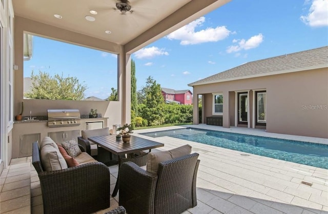 view of swimming pool featuring a patio area, ceiling fan, a grill, and an outdoor kitchen