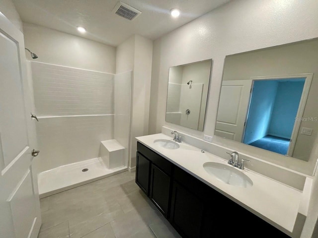 bathroom with tile patterned flooring, vanity, and walk in shower