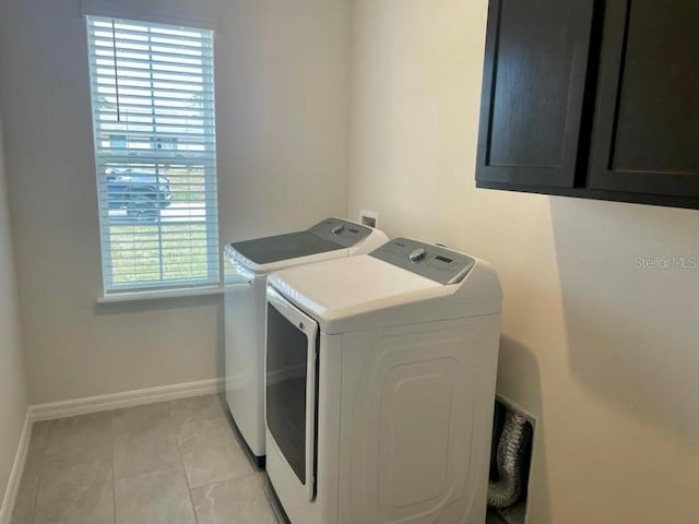 laundry room featuring separate washer and dryer, light tile patterned floors, and cabinets