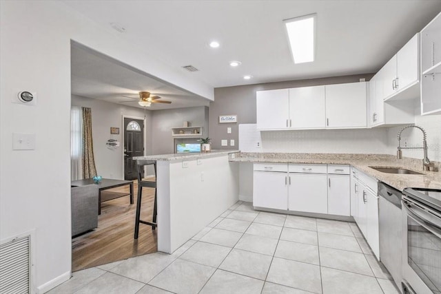 kitchen with kitchen peninsula, a kitchen breakfast bar, white cabinets, and sink