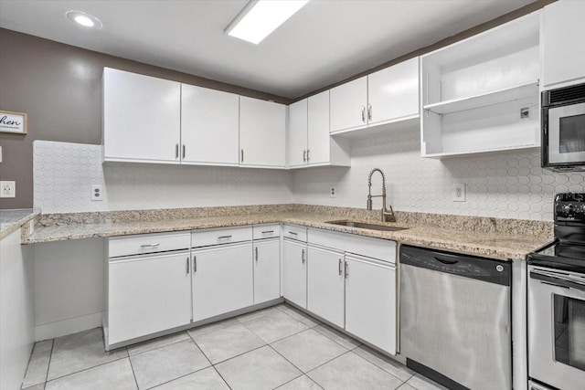 kitchen with light stone countertops, stainless steel appliances, sink, light tile patterned floors, and white cabinetry