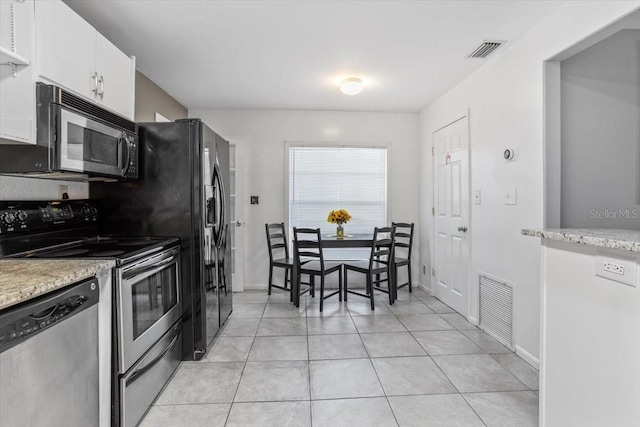 kitchen with light tile patterned flooring, light stone countertops, white cabinetry, and appliances with stainless steel finishes