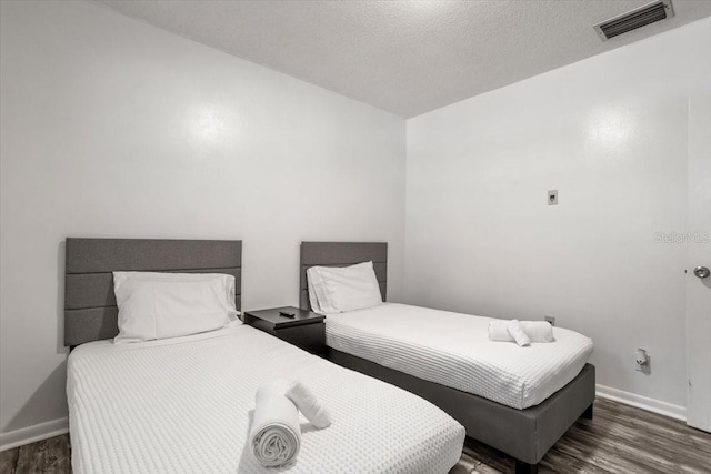 bedroom with a textured ceiling and dark wood-type flooring