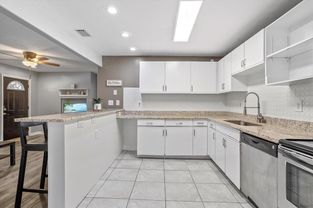 kitchen featuring sink, kitchen peninsula, a breakfast bar area, white cabinets, and appliances with stainless steel finishes