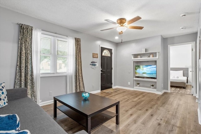 living room featuring a textured ceiling, light hardwood / wood-style flooring, and ceiling fan