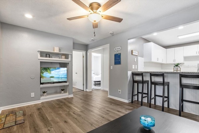 unfurnished living room with ceiling fan, dark hardwood / wood-style floors, and a textured ceiling