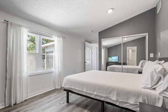 bedroom featuring hardwood / wood-style flooring, lofted ceiling, and a textured ceiling