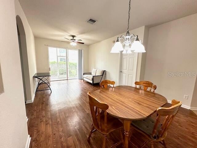 dining space with dark hardwood / wood-style flooring and ceiling fan with notable chandelier