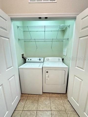 washroom featuring hookup for a washing machine, washer and clothes dryer, and light tile floors