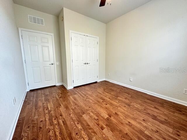 unfurnished bedroom featuring dark wood-type flooring, a closet, and ceiling fan