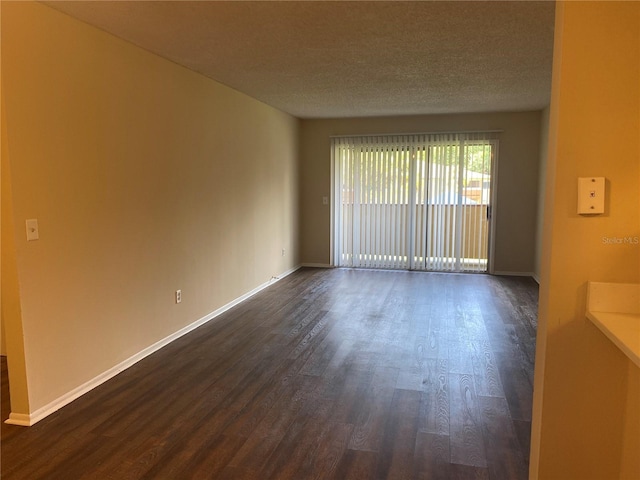 spare room with dark hardwood / wood-style floors and a textured ceiling