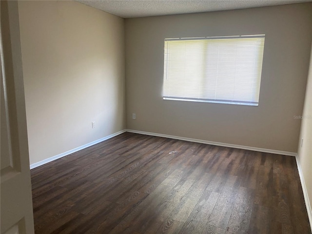 empty room with dark hardwood / wood-style floors and a textured ceiling