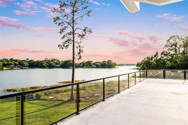 patio terrace at dusk with a yard and a water view