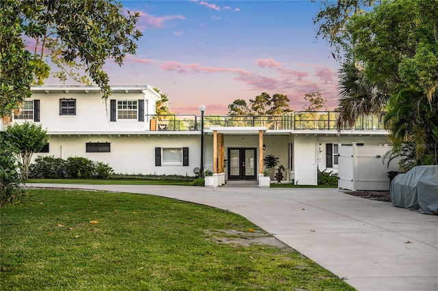 view of front of property with french doors and a lawn