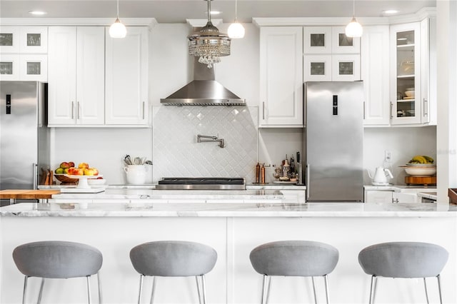 kitchen with white cabinets, light stone countertops, backsplash, and stainless steel fridge