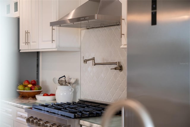 kitchen featuring wall chimney exhaust hood, white cabinets, and stove