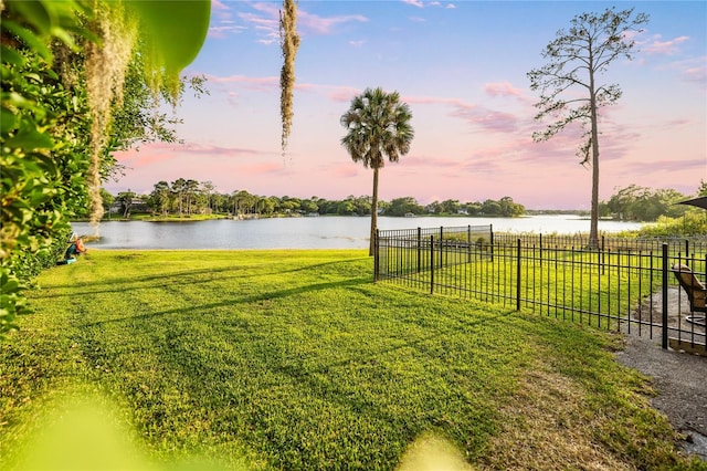 yard at dusk featuring a water view