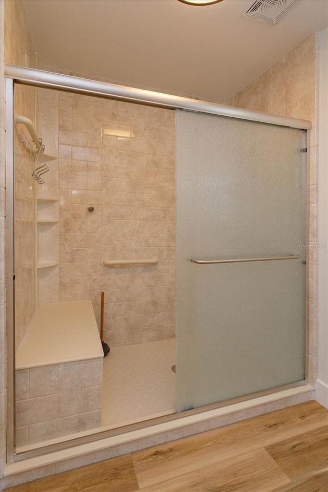 bathroom with wood-type flooring and a shower with shower door