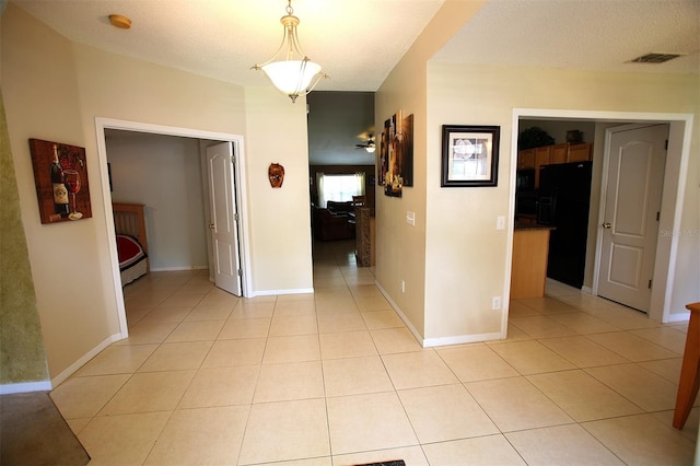 hallway with a textured ceiling and light tile floors