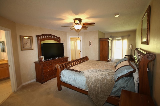 bedroom with light colored carpet, a textured ceiling, ceiling fan, and ensuite bathroom