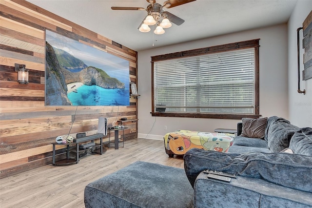 living room with light hardwood / wood-style floors, ceiling fan, and wooden walls