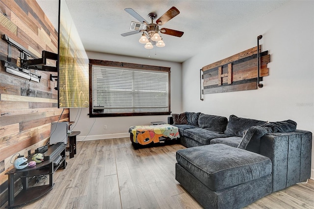 living room featuring wood-type flooring, a textured ceiling, and ceiling fan