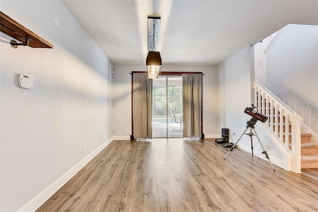 unfurnished room with a textured ceiling and light wood-type flooring