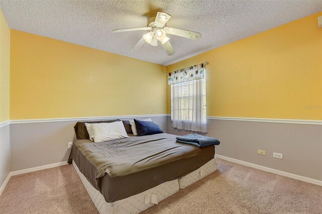 carpeted bedroom featuring ceiling fan and a textured ceiling