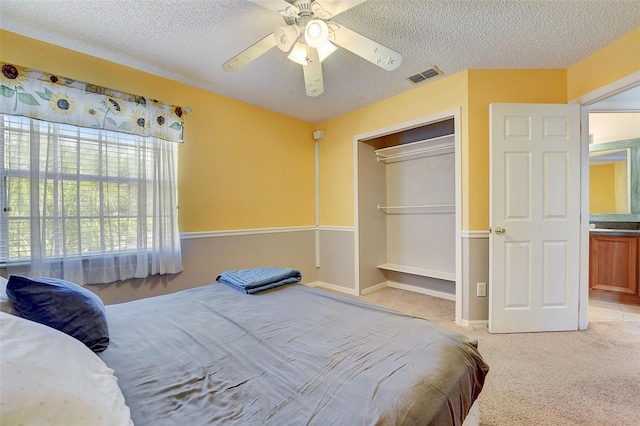 carpeted bedroom featuring a closet, a textured ceiling, and ceiling fan